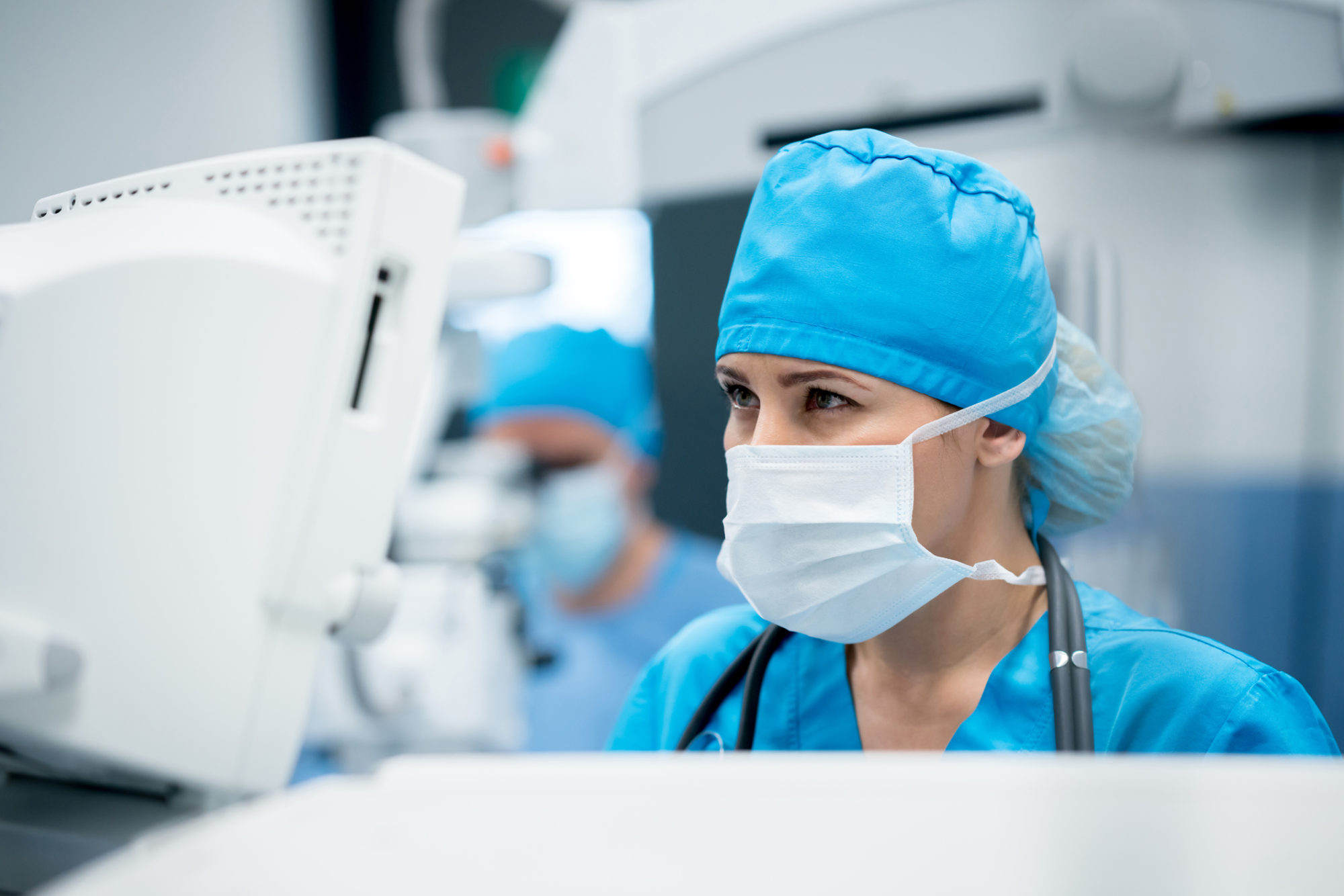 Portrait of a female surgeon checking vitals on a patient at the operating room - healthcare and medicine concepts