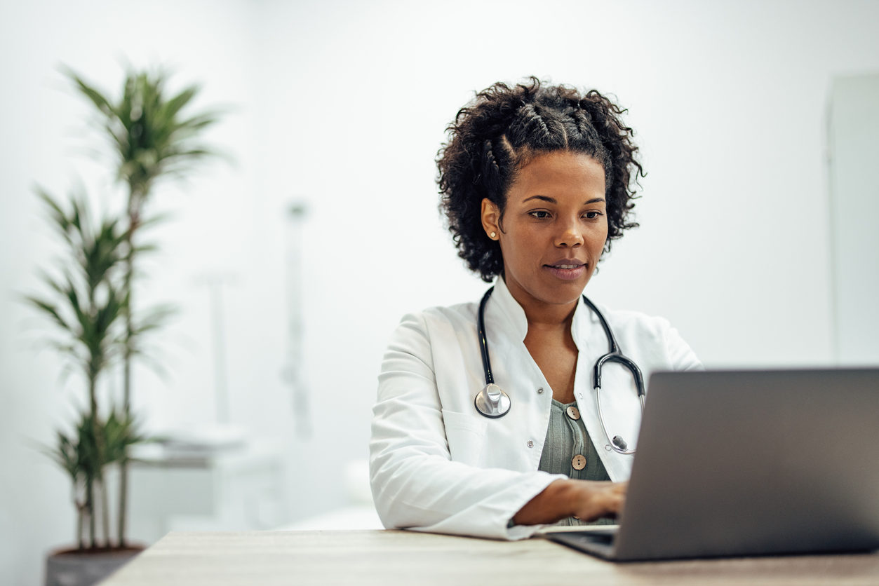 Smiling doctor using laptop while working in private practice.