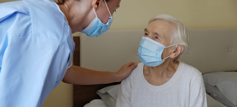 Mature female in elderly care facility gets help from hospital personnel nurse. Senior woman with aged wrinkled skin & care giver, hands close up. Grand mother everyday life. Background, copy space.