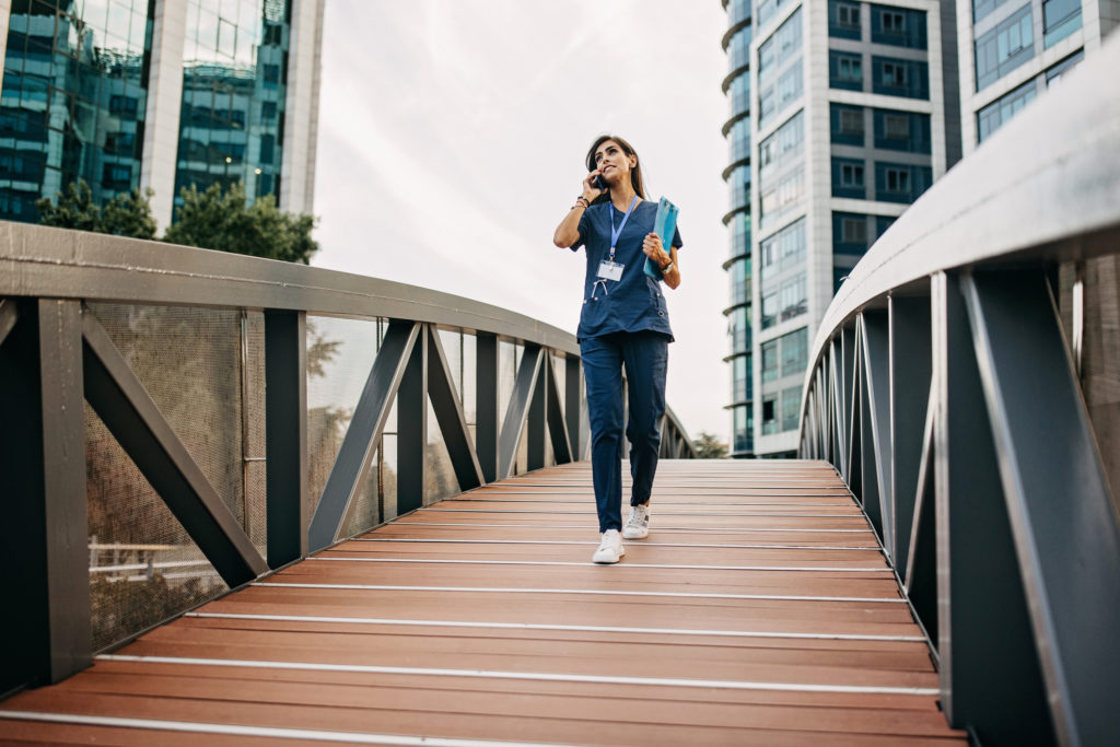 A women doctor uses her smartphone as she walks to work.